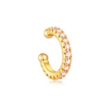 Gold ear cuff with baby pink pavé stones in a minimal curved design on a white background